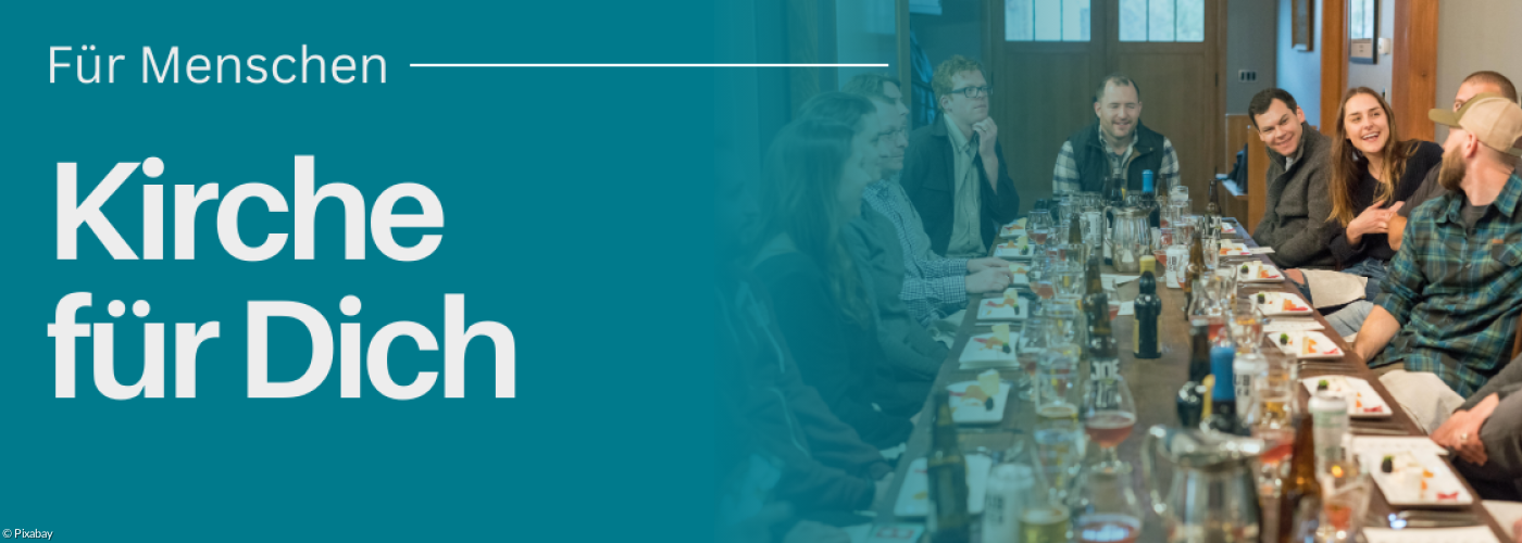 Menschen sitzen zusammen an einem langen Tisch und Essen gemeinsam.