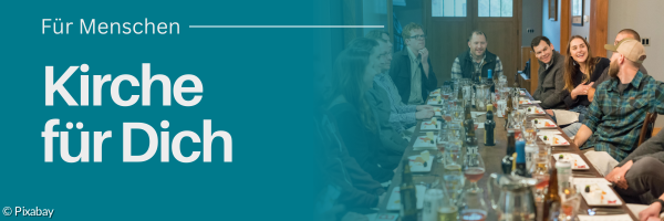 Menschen sitzen zusammen an einem langen Tisch und Essen gemeinsam.