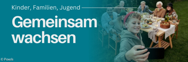 Jugendlicher der ein Selfie macht, mit einem Tisch von Menschen im Hintergrund auf einem grünen Rasen.