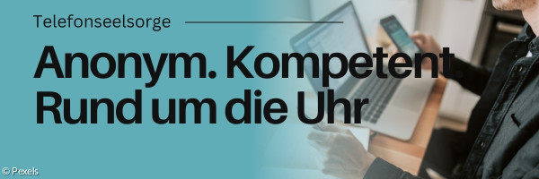 Jemand vor Laptop und Handy an einem Tisch.