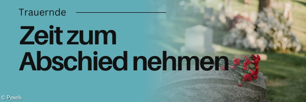 Grabstein mit Blumen darauf. Friedhof im Hintergrund.