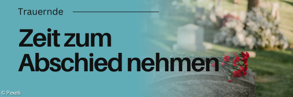 Grabstein mit Blumen darauf. Friedhof im Hintergrund.