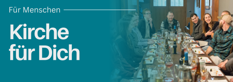 Menschen sitzen zusammen an einem langen Tisch und Essen gemeinsam.