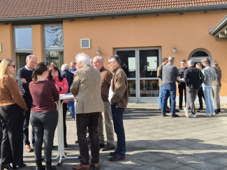 Menschen stehen in Gruppen an Stehtischen und sind in intensiven Gespräch