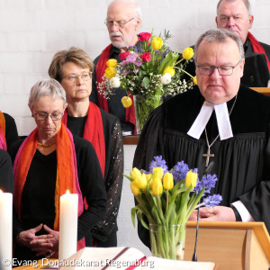 Dekan Jörg Breu steht hinter dem mit Tulpen geschmückten Altar. Im Hintergrund der Chor und spricht ein Gebet.